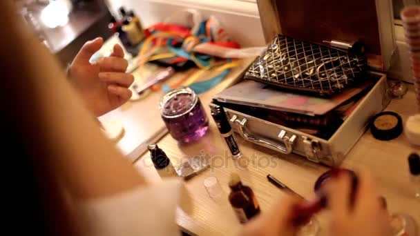Chica está sentada en el salón de arte de la maquilladora y ella está haciendo maquillaje de moda . — Vídeos de Stock