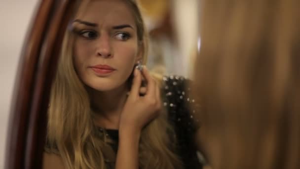 Portrait of a beautiful well-groomed girl trying on jewelry in front of the mirror. Beautiful woman trying on earrings in front of the mirror. close-up — Stock Video