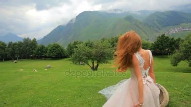 Dağlar bakarken poz muhteşem gelin sarışın. Dağ manzarası olan bir arka planda çekici kız. Düğün günü
