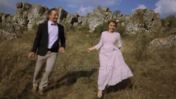 Um casal feliz a divertir-se no prado. casal correndo em torno do campo — Vídeo de Stock