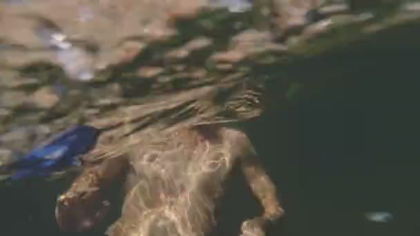 Beau mec se baigne dans la mer avec un bâton Selfie sur le fond d'un rocher. Tournage sous-marin . — Video