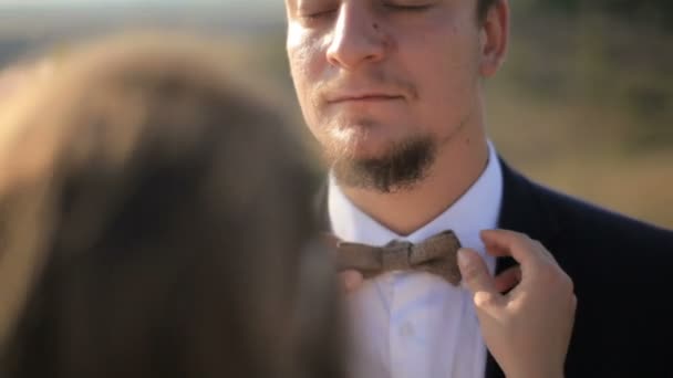 Дівчина пристосовує краватку-бабочку до коханця — стокове відео