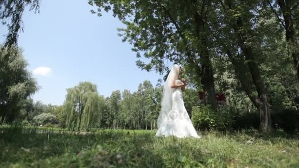 Грустная невеста, стоящая у пруда в парке — стоковое видео
