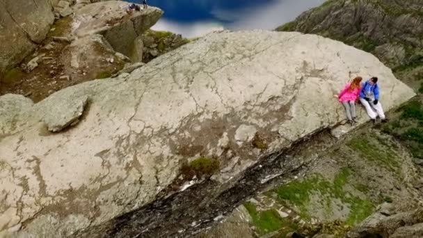 Норвегия. парень и девушка, сидящие на краю Тролля — стоковое видео