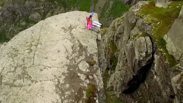 Noruega. cara e menina sentado na borda da Trolltunga — Vídeo de Stock