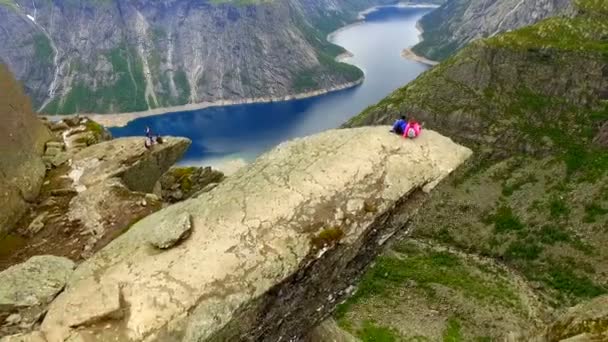 Norway. guy and girl sitting on the edge of the Trolltunga — Stock Video