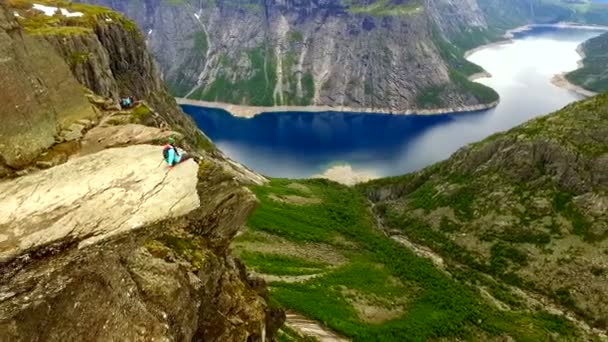 Noruega. menina sentada na borda do Trolltunga — Vídeo de Stock