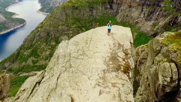 Noruega. chica está de pie en el borde de la Trolltunga — Vídeo de stock