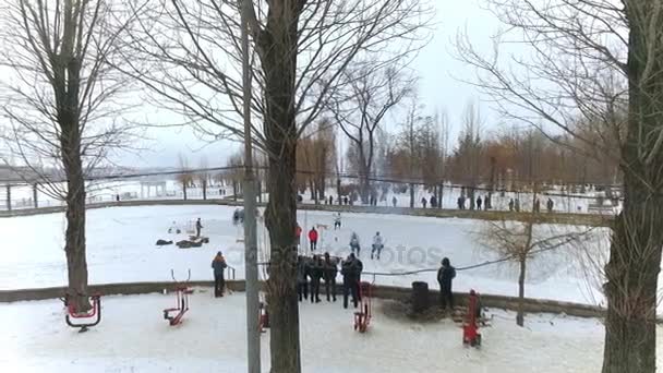 Aero zicht op het stadspark voor de winter. mannen spelen hockey op een bevroren meer in een stadspark. Winter familieplezier. Wintersport. Ijshockey. Winteractiviteiten. Winter spelen — Stockvideo