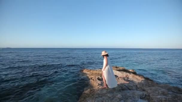 Красивая девушка в белом платье сидит на пляже. Греция — стоковое видео