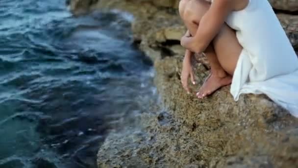 Όμορφη κοπέλα με λευκό φόρεμα κάθεται στην παραλία. Ελλάδα — Αρχείο Βίντεο