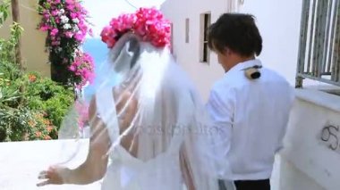 Düğün günü. Gelin ve damat denize çiçek ile güzel bir caddede gidiyor.