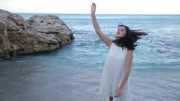 하얀 드레스를 입고 아름 다운 소녀는 해변에 서 있다. 그리스 — 비디오