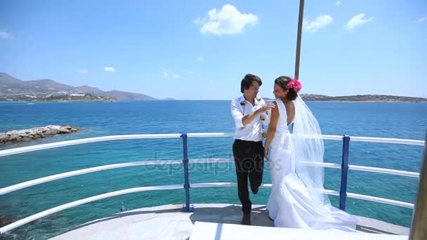 Νεαρό ζευγάρι όμορφη στέκεται στην αποβάθρα της θάλασσας και αγκαλιάζει στην ημέρα του γάμου τους. — Αρχείο Βίντεο