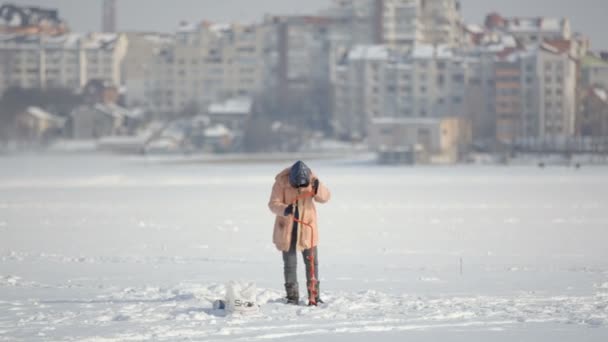 Fishermen on ice on a frozen lake near the city park — Stock Video