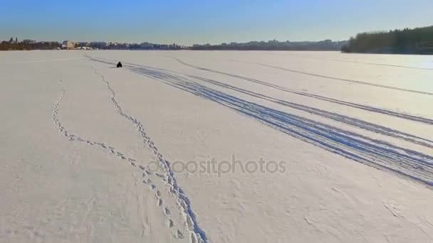 Diversão de inverno. Uma viagem numa mota de neve. Dois caras estão montando uma moto de neve sobre gelo congelado lago — Vídeo de Stock
