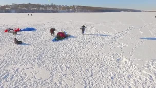 Вид сверху. Летчики состязаний на параплане на замерзшем озере возле городского парка . — стоковое видео