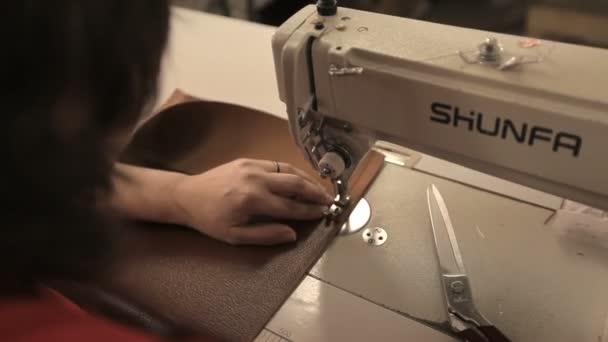 Woman sews new leather case for couch behind sewing machine. — Stock Video