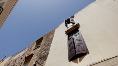 Mavi gökyüzüne karşı ahşap kepenkleri ile açık pencereleri ile eski ev