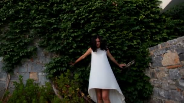 Странный сон. Девушка над пропастью на фоне высокой стены в плющом — стоковое видео