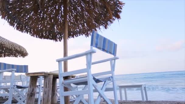 Ontspan op het strand in een strandstoel onder een paraplu. — Stockvideo