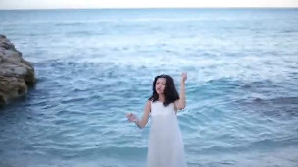 Hermosa chica en vestido blanco está de pie en el mar — Vídeo de stock