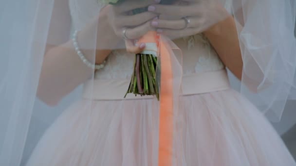 Όμορφη νύφη κάτω από ένα πέπλο με ένα μπουκέτο από λουλούδια. Μυστηριώδης εικόνα — Αρχείο Βίντεο