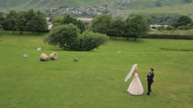 damat ve gelin güzel dağlar, Kazbegi, Gürcistan yeşil çim üzerinde zevk elbise