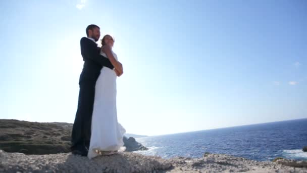 快乐新郎拥抱新娘从后面的希腊海滩 婚礼日概念 — 图库视频影像