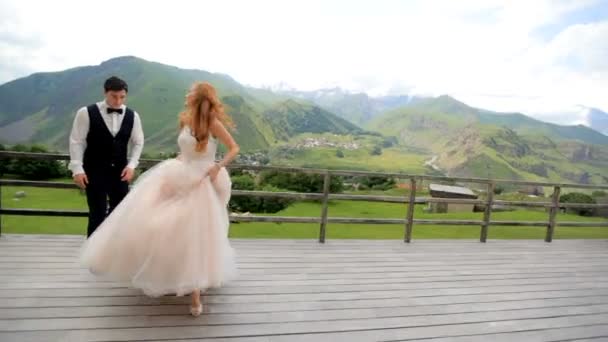 Día de la boda. Feliz recién casados divertirse contra el telón de fondo de las montañas . — Vídeo de stock