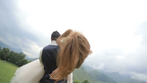 Svatební den. Šťastní novomanželé bavit na pozadí hor. — Stock video