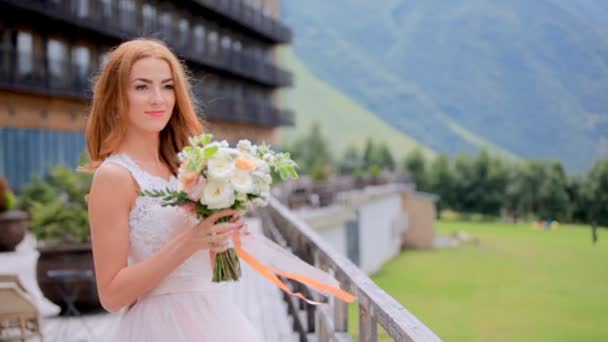Невеста блондинка расслабляется, глядя на горы. День свадьбы — стоковое видео