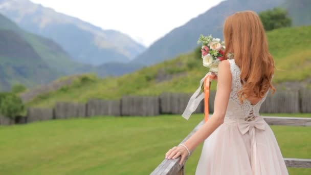 Красивая рыжая невеста на фоне гор — стоковое видео