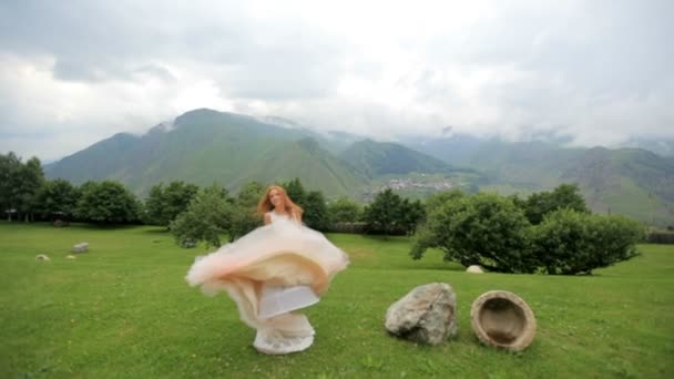 Hermosa novia pelirroja bailando sobre el fondo de las montañas. cámara lenta — Vídeo de stock