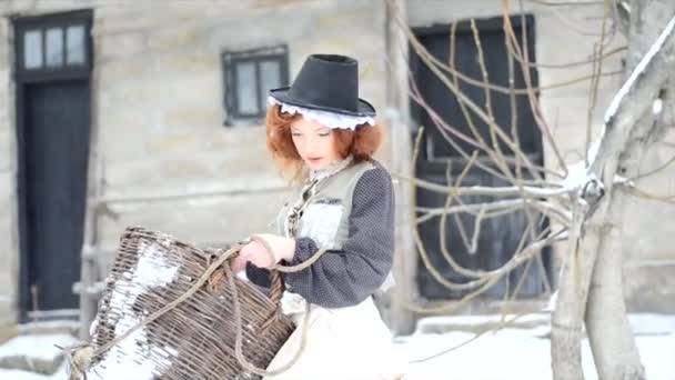 Bastante pelirroja chica con una cesta grande pasea por el patio de una casa de campo — Vídeo de stock