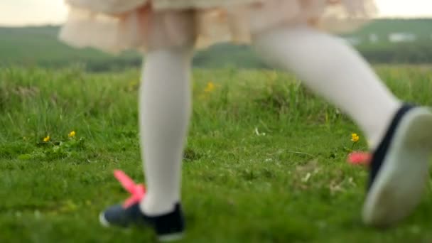 Two little girls are playing on a green meadow. Childrens feet. — Stock Video