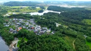 Nehir kenarındaki yeşil ormanın arasında çok güzel bir Norveç balıkçı köyünün havadan görünüşü. Güzel Norveç manzarası.