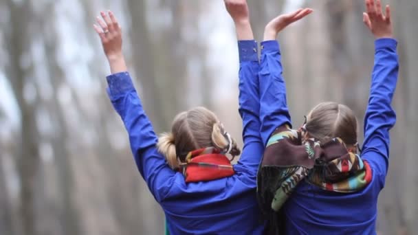 Dos chicas gemelas divirtiéndose en el bosque de otoño sentadas en un tronco. Concepto La felicidad lo significa todo . — Vídeo de stock