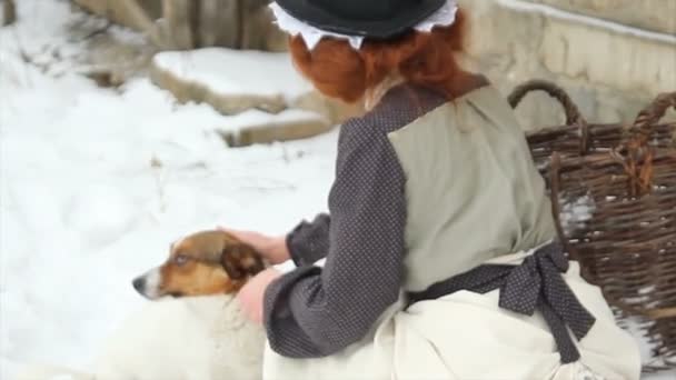 Piękna rudowłosa dziewczyna w etnicznych ubraniach z psem na dziedzińcu wiejskiego domu — Wideo stockowe