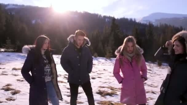 Drie meisjes en een jongen hebben plezier tegen de blauwe lucht op een zonnige winterdag. Het concept van een gezonde levensstijl en buitenactiviteiten voor adolescenten — Stockvideo