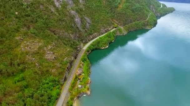 Вид с воздуха. Автомобиль едет по шоссе вдоль реки среди гор. Норвегия — стоковое видео