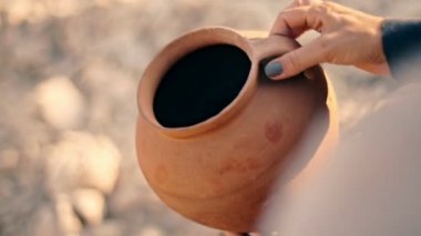 Bir kadın boş bir sürahide kum döker. Suyun ekonomik kullanımı kavramı .