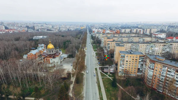 Veduta aerea di una strada con case prefabbricate a più piani, una chiesa, un parco e un'autostrada all'inizio della primavera . — Foto Stock