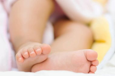 yatakta uyuyan sevimli Asya bebek küçük ayakları