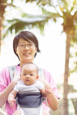 Anne ve bebek taşıyıcı, açık havada portre onun bebek kız