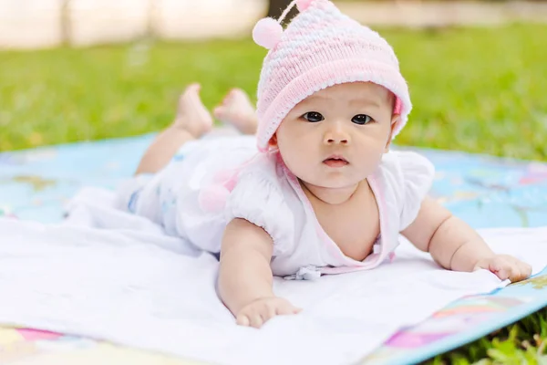 Asiático bebê mentira propenso no chão no parque Fotografia De Stock