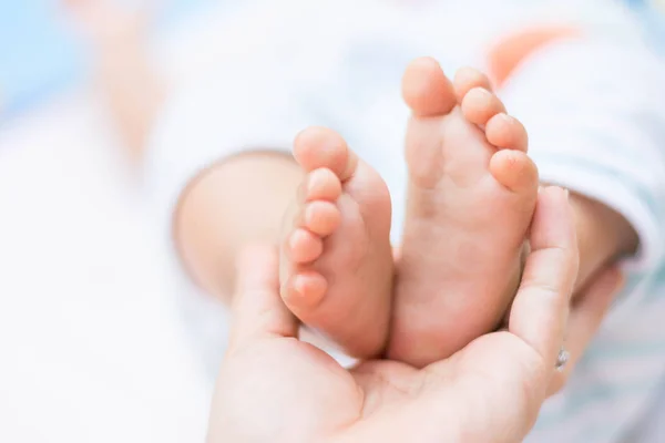 Mani della madre che tengono piccoli piedi del bambino — Foto Stock