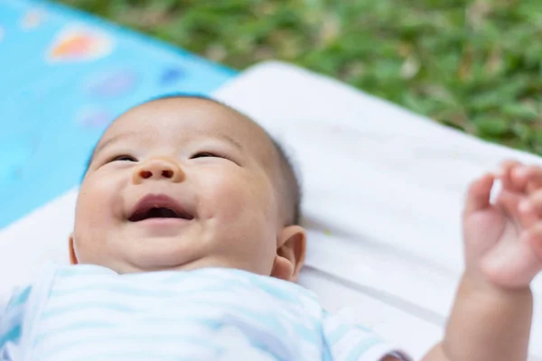 Smilling と地面にアジアの赤ちゃんうそをカットします。 — ストック写真