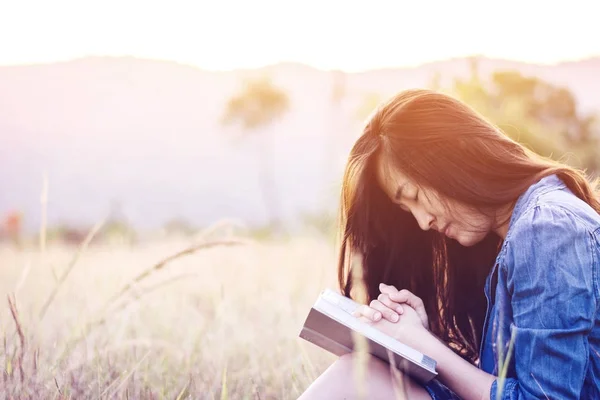 그라데이션 석양에 풀밭에서 여자 읽기 책 로열티 프리 스톡 이미지