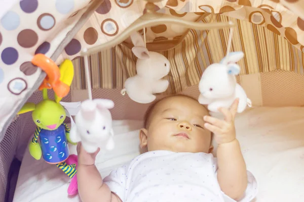 Niedliche entzückende Neugeborenes spielt auf bunten Spielzeug Turnhalle Stockfoto